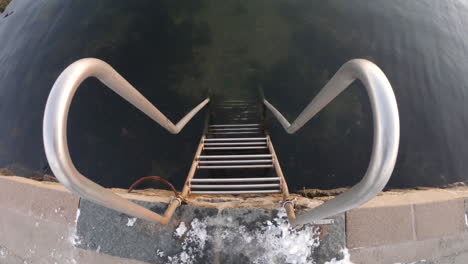 4k close-up shot of a small metal staircase by the cold ocean sea water on a winter day in sweden