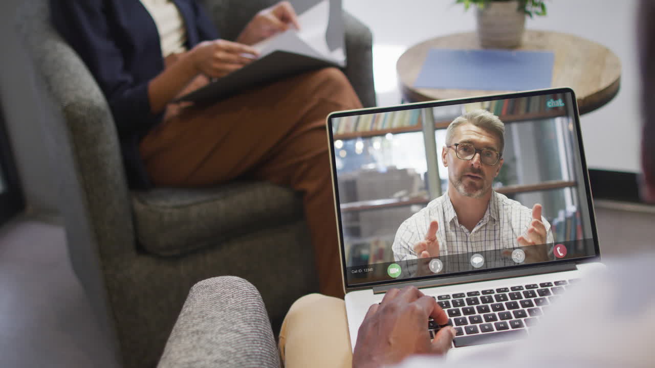African american businessman using laptop for video call with caucasian business colleague