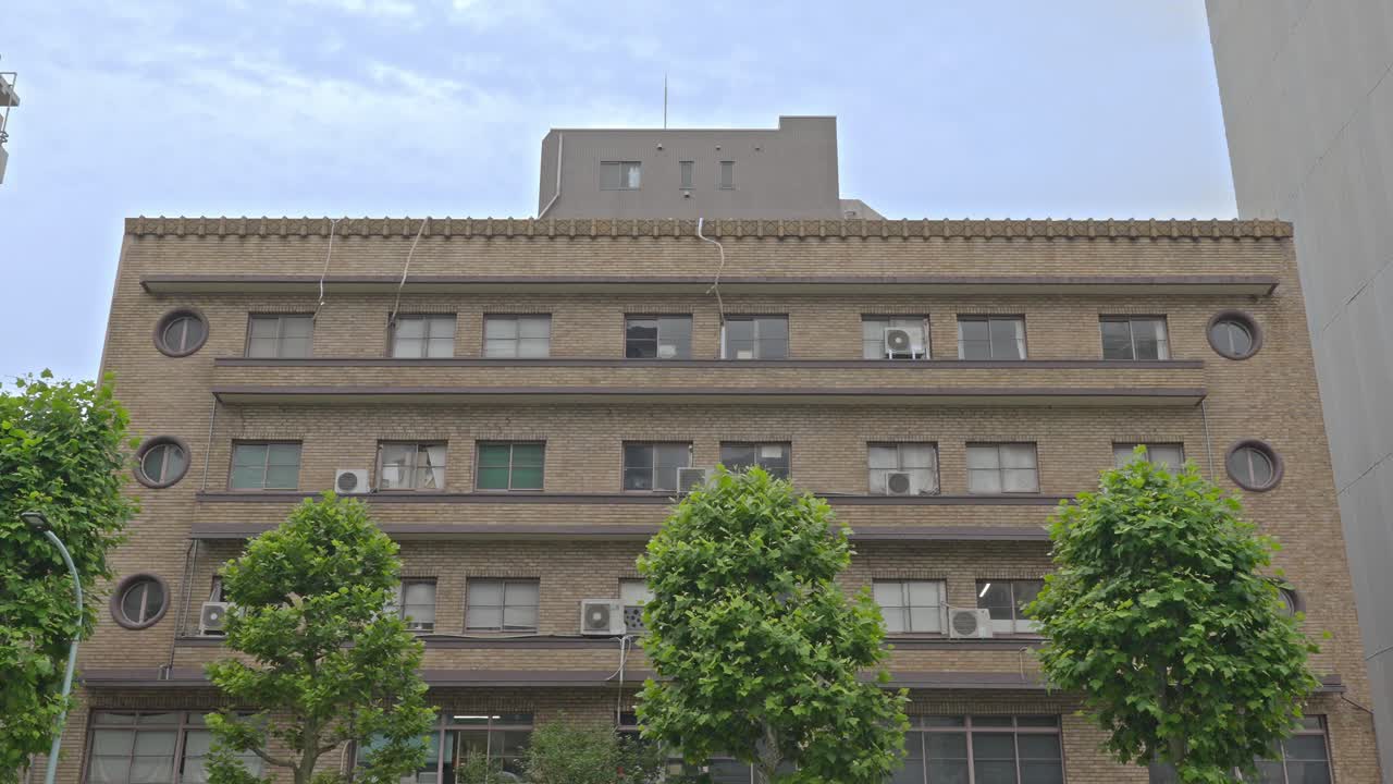 The stately facade of the Tiger Building in Kuramae, Tokyo, showcasing its unique circular windows and a blend of classic design and urban history.