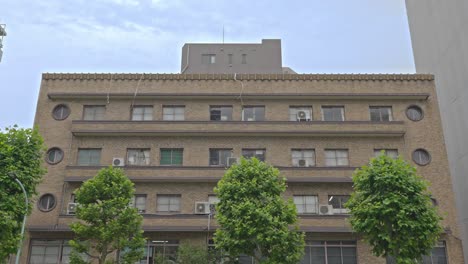 the stately facade of the tiger building in kuramae, tokyo, showcasing its unique circular windows and a blend of classic design and urban history.