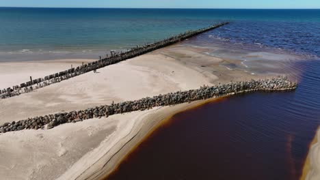 On-the-bed-of-the-Holy-river-flowing-into-the-Baltic-Sea,-on-the-left-bank,-stones-are-laid-along-the-remains-of-an-old-bridge-on-the-beach
