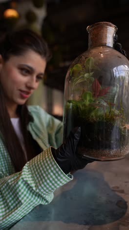 woman examining a terrarium in a cafe