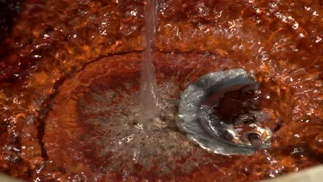 Still-shot-of-running-water-into-a-rusty-sink-in-public-fountain