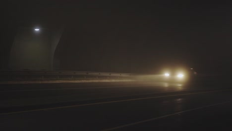 los coches circulan a gran velocidad bajo un puente oscuro en una noche nublada