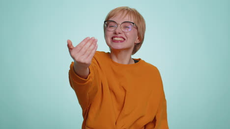 Young-happy-blonde-woman-in-glasses-spread-hands-and-give-hug-embrace-to-you-on-blue-background