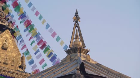 roof structure in a buddhist temple with colorful prayer flags and blue sky on the background. - close up shot