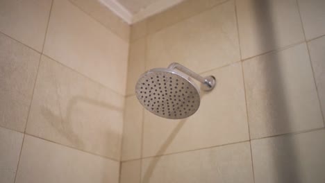 slow moving camera shot of aluminum shower interior at hotel. light beige color tiles in wall background.