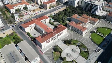 Aerial-drone-footage-of-the-University-of-Athens,-shifting-from-the-front-to-the-side,-showcasing-road-traffic-around,-in-summer,-Greece