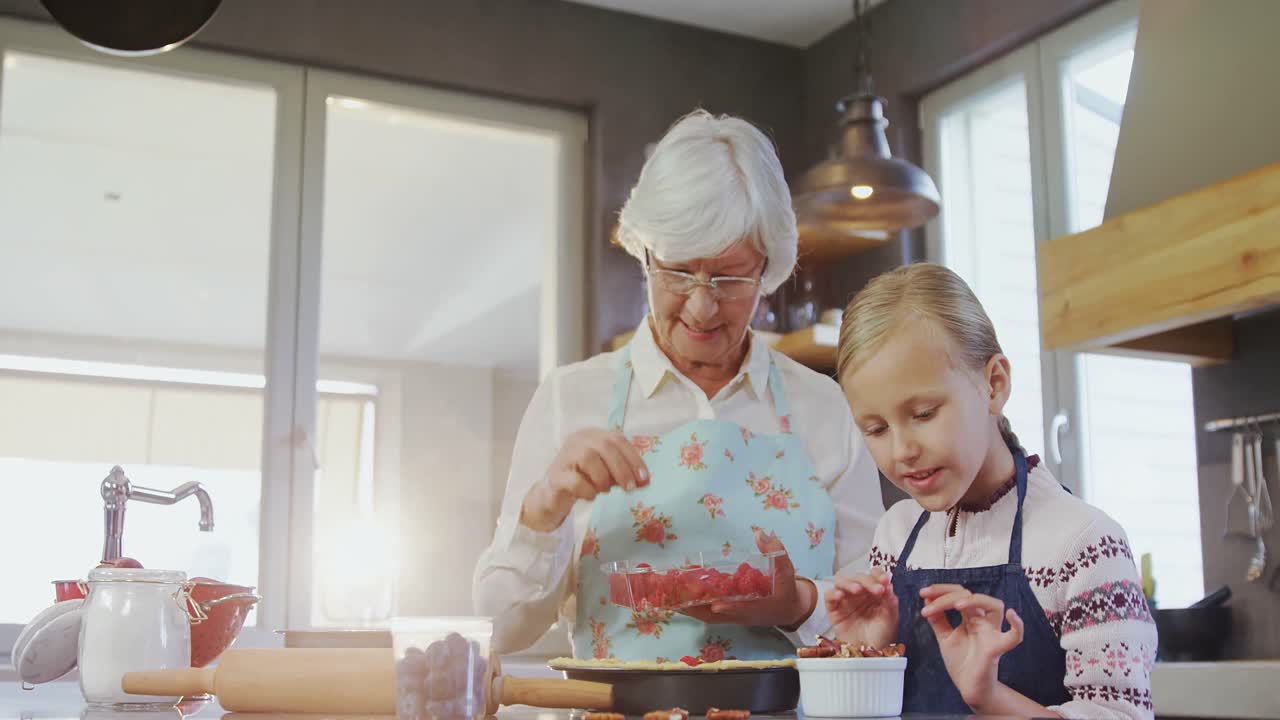 Grandmother and granddaughter plating the pie with strawberries 4k