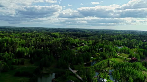 Toma-Aérea-Hacia-Atrás-Del-Parque-Nacional-Con-Lago-Y-Apartamentos-Durante-El-Día-Soleado---Amatciems,-Letonia