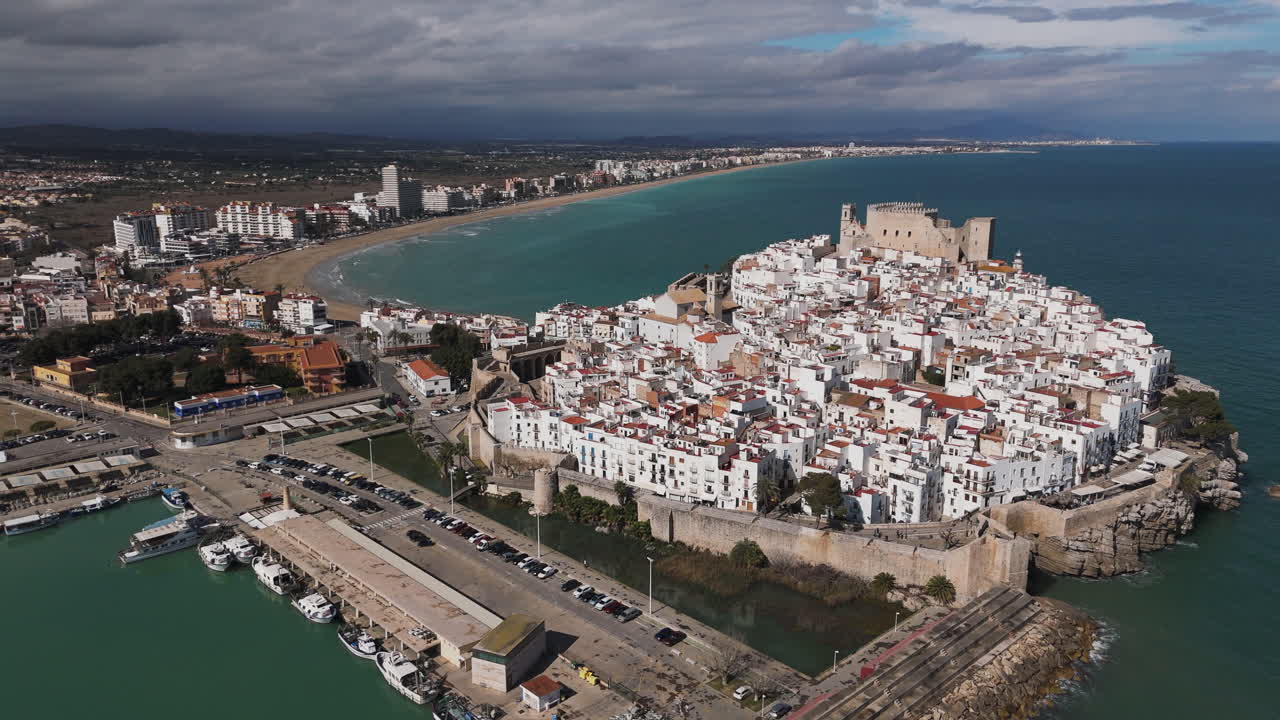 Castle and harbor of Peniscola seen from above with boats and sunny sea coastline visible