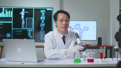 asian scientist man holding petri dish and talking to camera