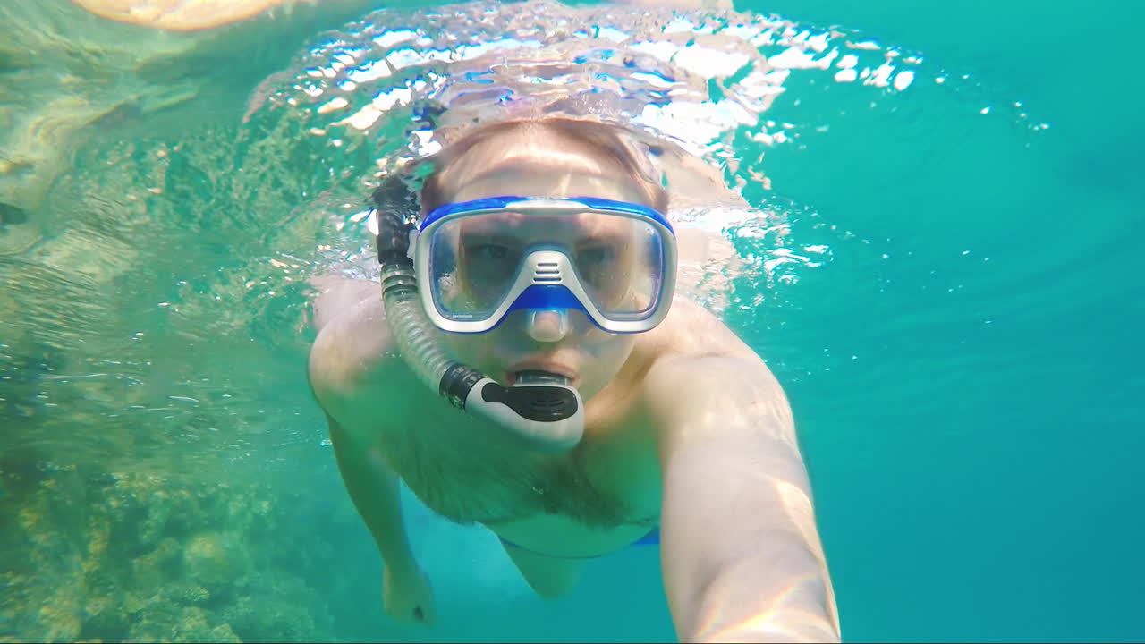 한 남자가 다이빙을 위해 마스크를 쓰고 물속에서 수영한다