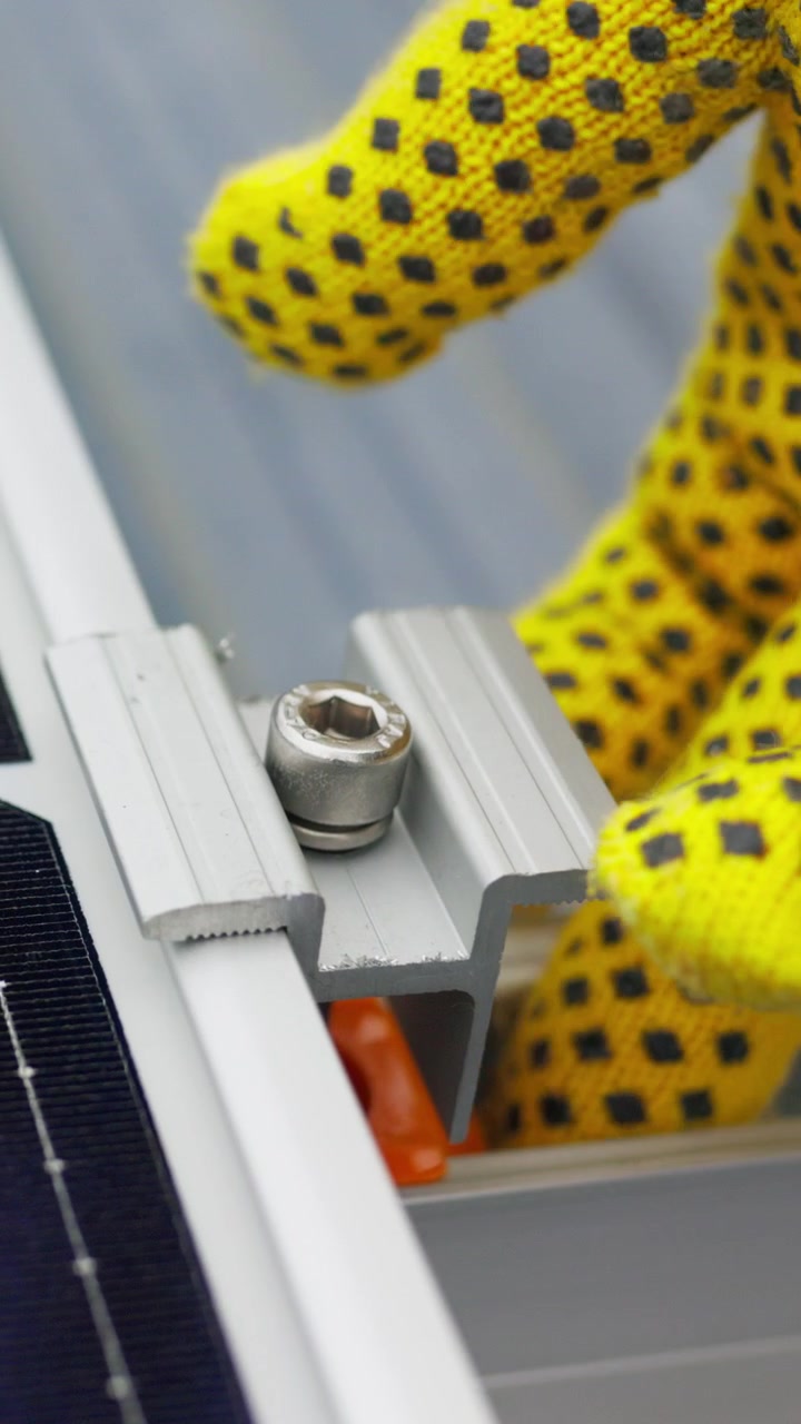 A worker in yellow gloves installs a solar panel bracket highlighting the process of renewable