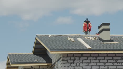 male builder laying tiles on the roof of the house