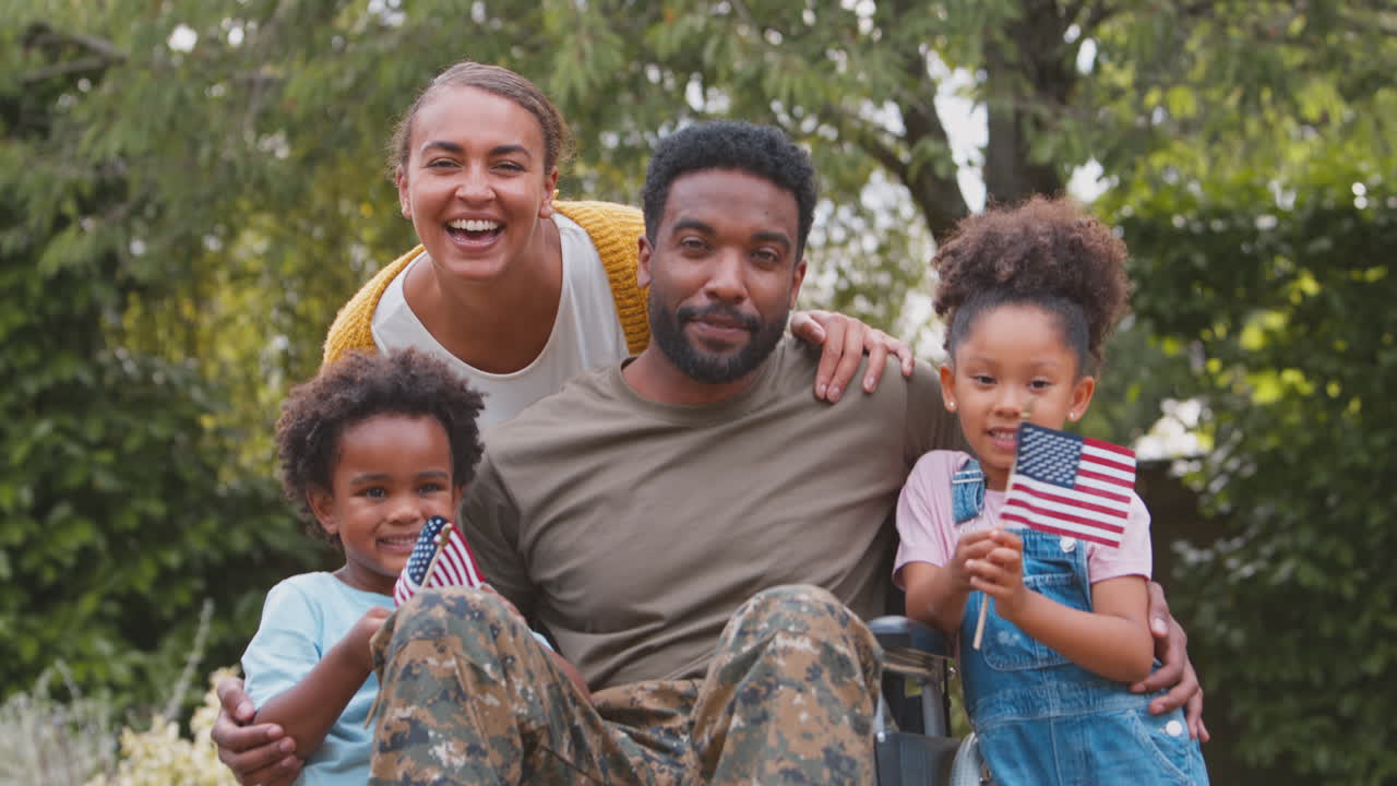 American Army Family Outdoors In Garden With Injured Father In Wheelchair