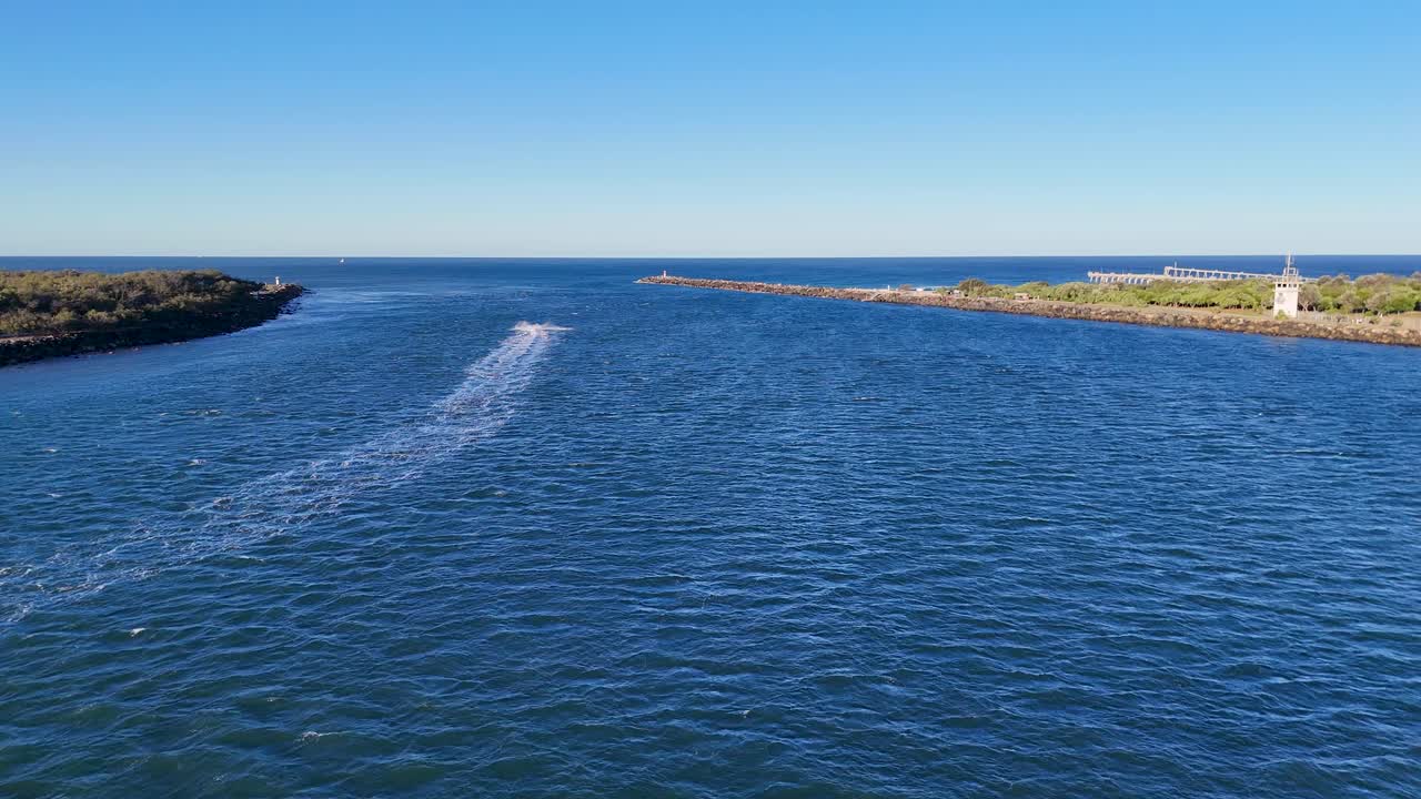 Drone footage captures serene ocean waves and coastline under clear skies at Gold Coast, Australia, during sunset