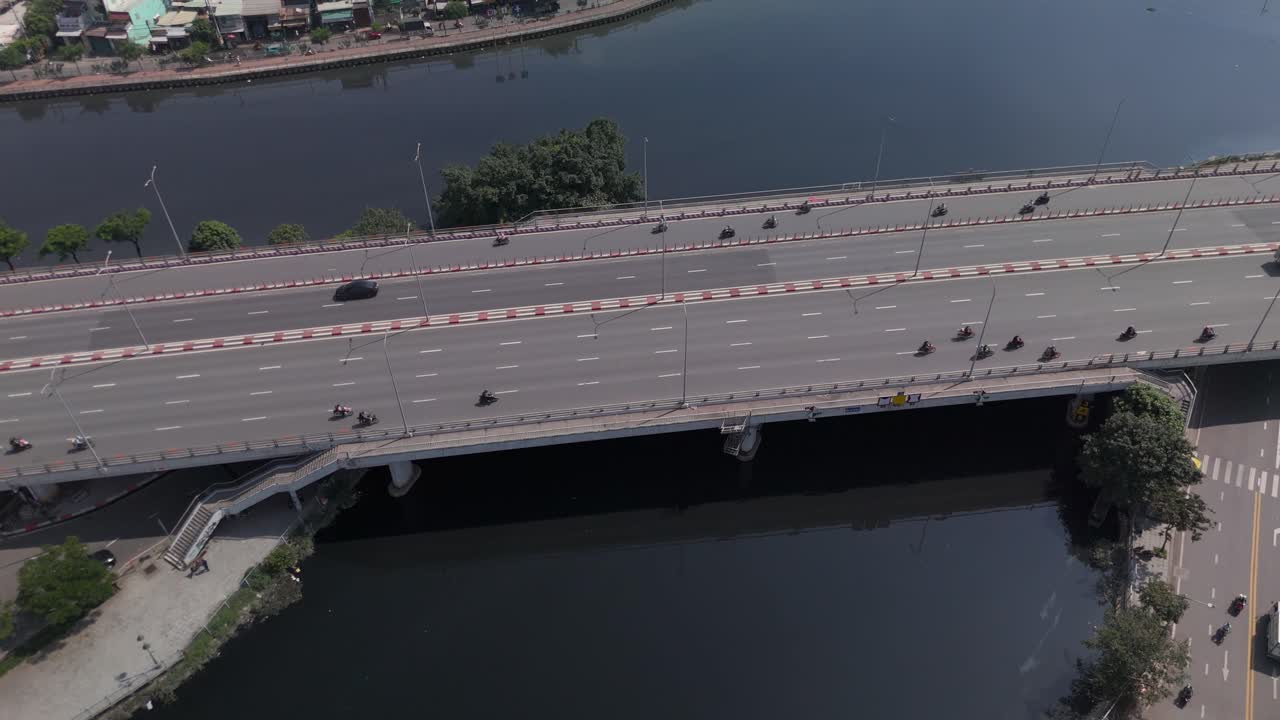 Aerial view of busy freeway over river with urban sprawl on sunny clear day top down rotation
