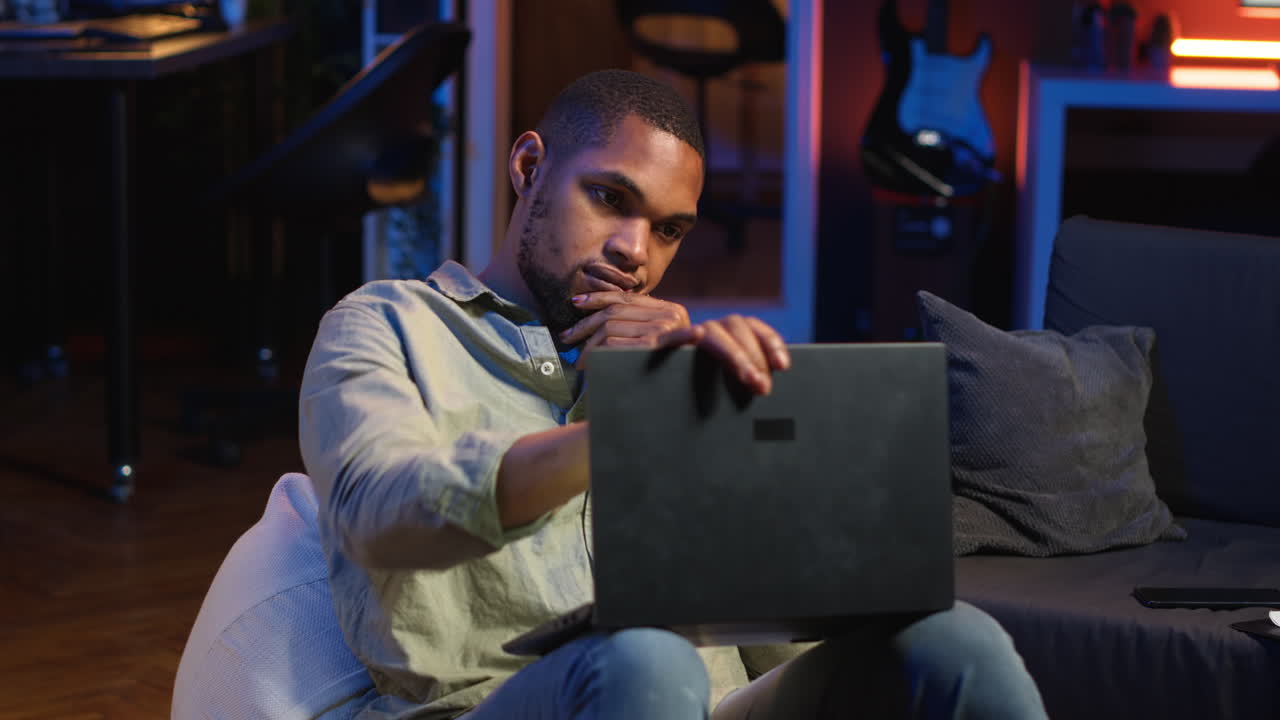 Vertical Video Black man taking a break from work by scrolling his smartphone at home