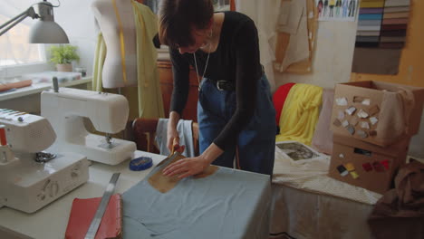 female dressmaker cutting fabric with scissors