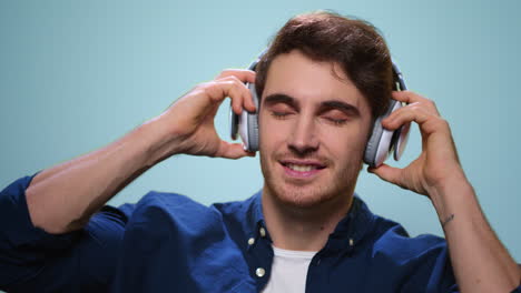 smiling man putting on headphones in studio. guy listening music in earphones