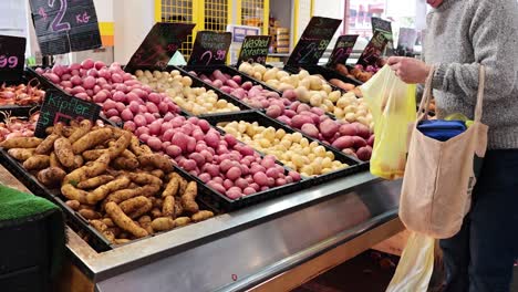 person picking potatoes at a market stall