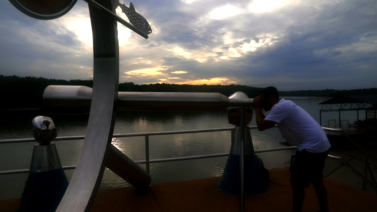 남자가 해변에서 망원경을 통해 보고 있다