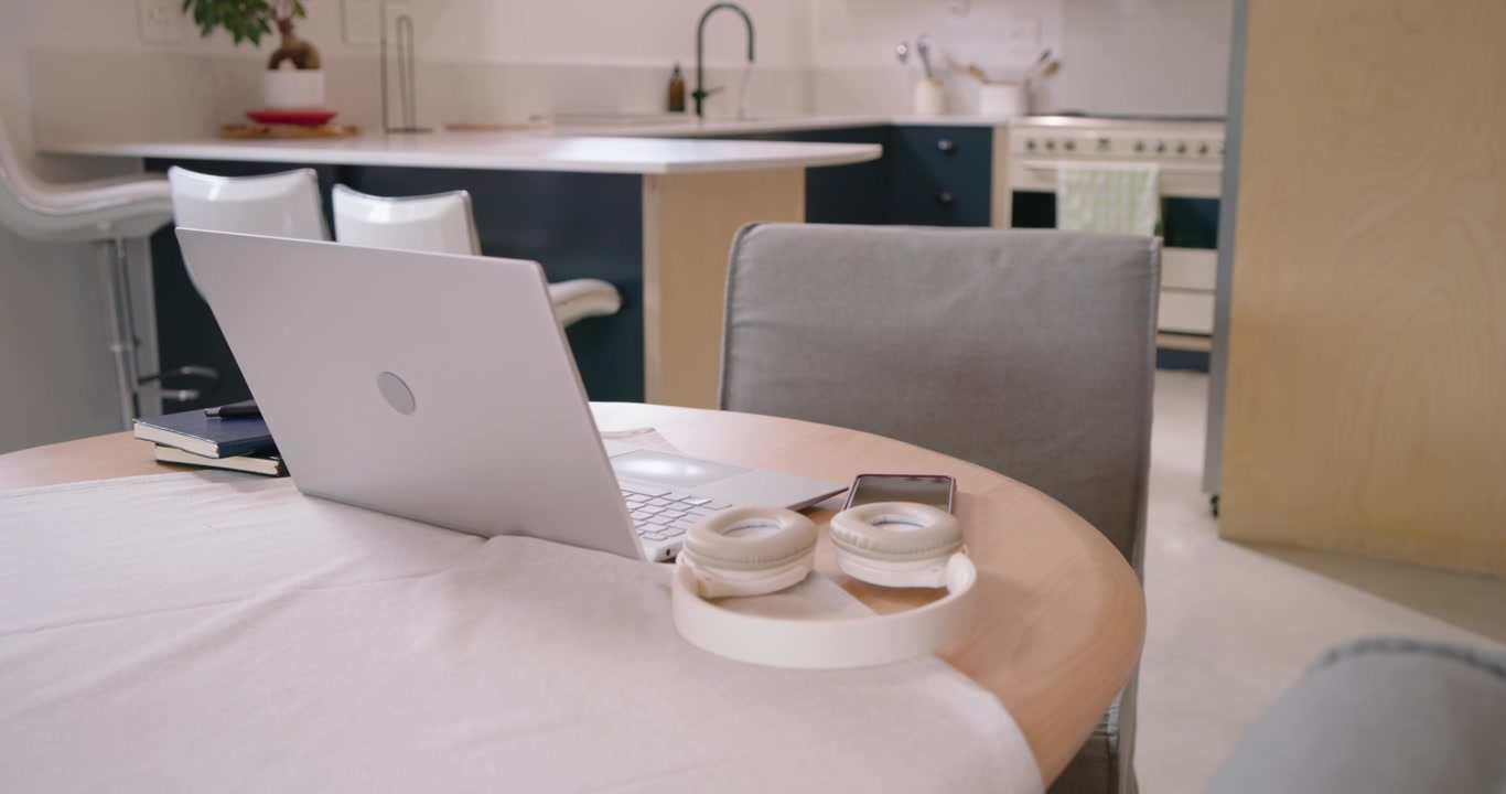 Camera is moving closer, revealing laptop and headphones on round table to show smartphone