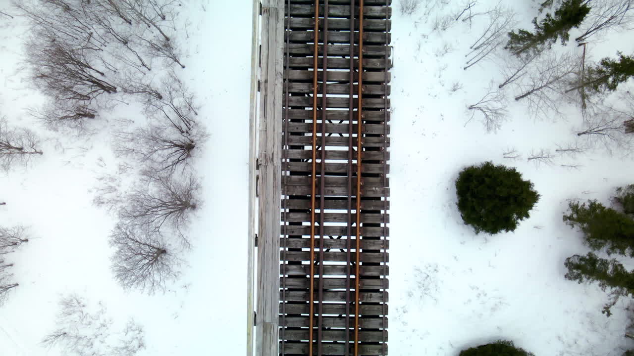 겨울에 지상에 눈이 내리는 기차 다리 위의 드론 비행