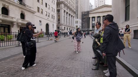 tourists gather in front of new york’s iconic fearless girl statue on broad street in downtown manhattan