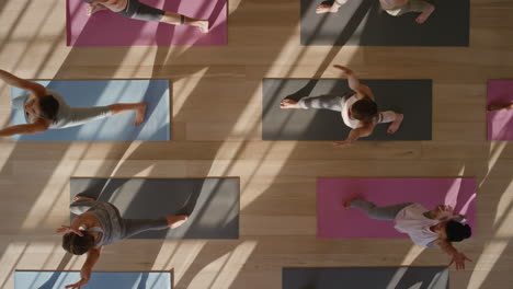 Vista-Superior-Clase-De-Yoga-Mujeres-Sanas-Practicando-Pose-Guerrera-Disfrutando-De-Un-Estilo-De-Vida-Fitness-Haciendo-Ejercicio-En-El-Estudio-Al-Amanecer