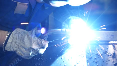 anonymous workman welding metal construction in workshop