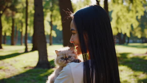 woman holding her fluffy cat in a sunny park