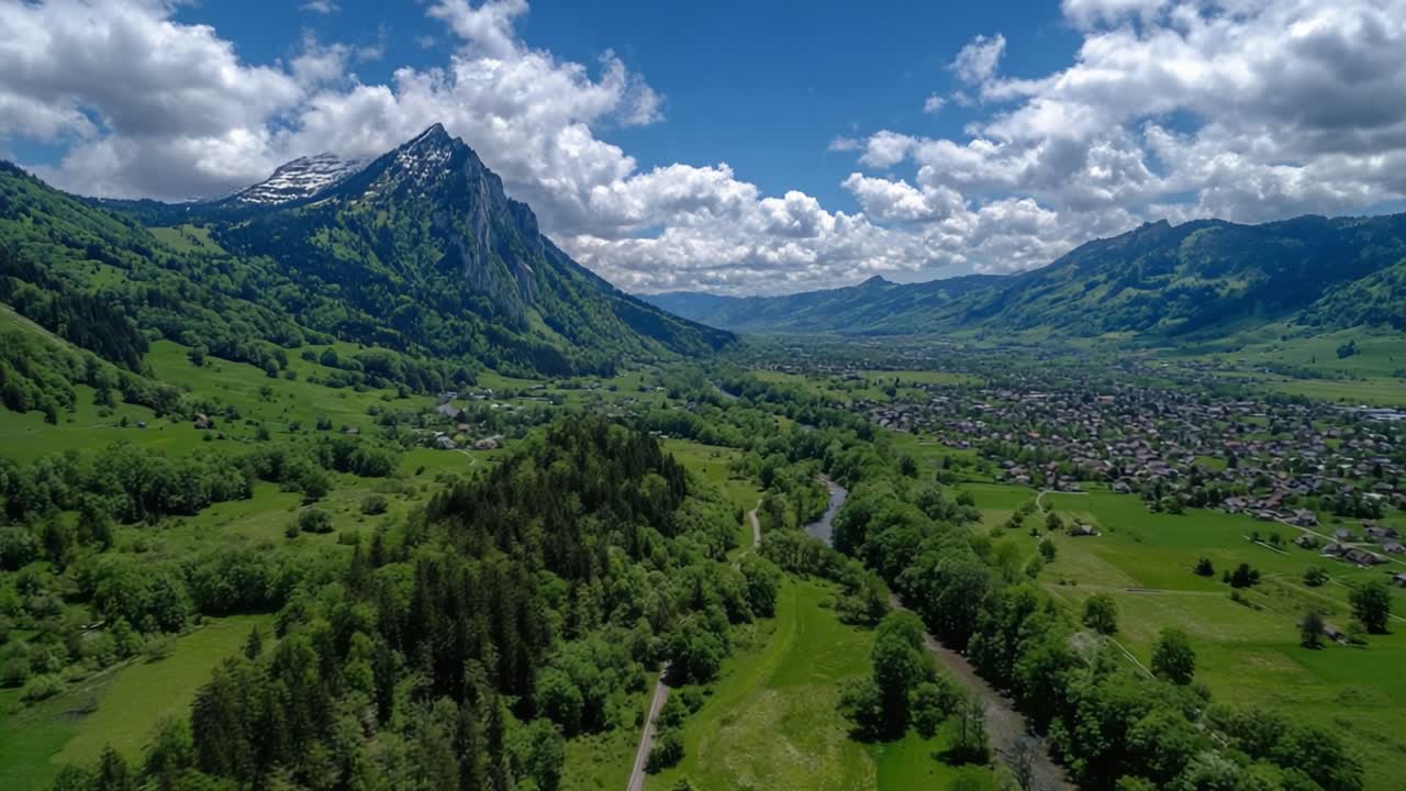 Vista Aerea di una Valle Rigogliosa Sotto una Maestosa Catena Montuosa, Evidenziando Paesaggi Verdi Lussureggianti e un Fiume Scenografico Che Scorre Attraverso un Territorio Pittoresco