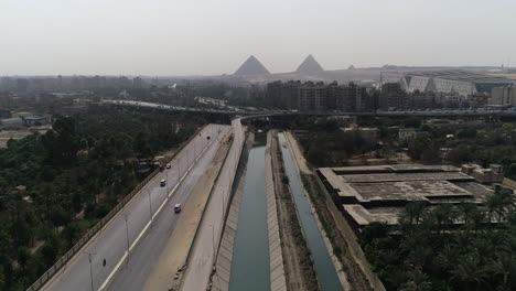 Aerial-Shot-for-The-Pyramids-of-Egypt-in-Giza-beside-a-branch-from-the-River-Nile-in-the-foreground-Maryotya-branch