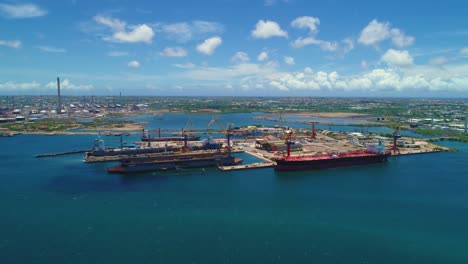 Shipping-container-barges-docked-in-marine-transport-logistics-dock-moving-goods,-aerial-panoramic-drone