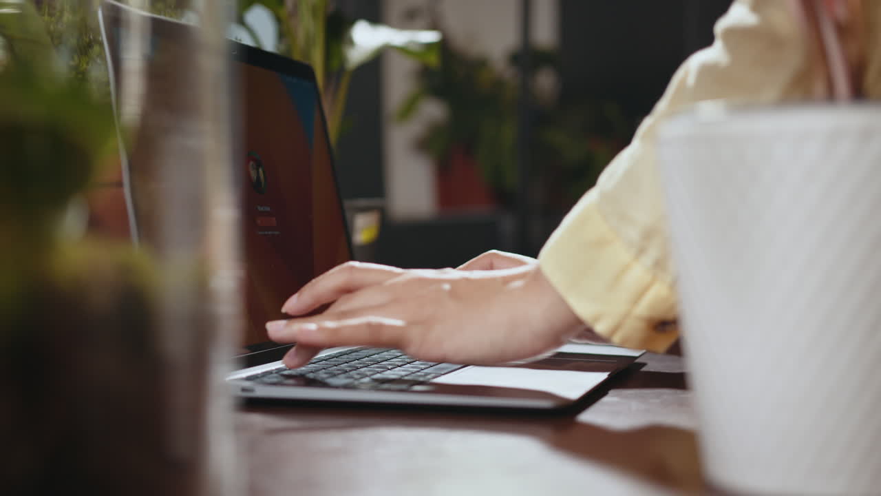 persona escribiendo en una computadora portátil en un escritorio de la oficina en casa con plantas