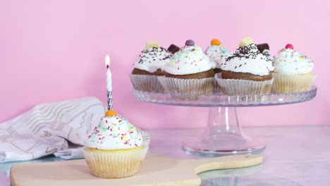 lighting up birthday candle on cup cake served on the table