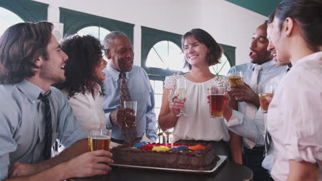 mujer de negocios soplando velas en pastel de cumpleaños en una celebración en un bar con colegas