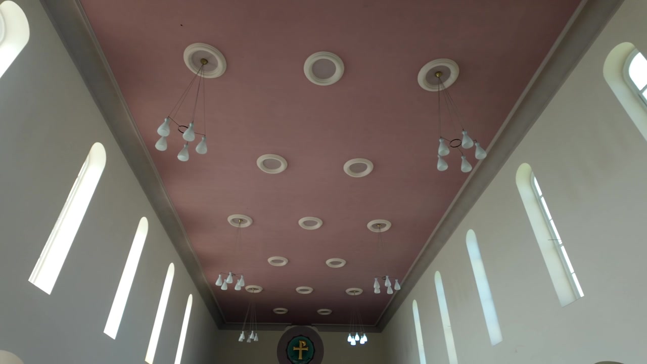 Panoramica a sinistra attraverso le luci del soffitto della chiesa e le finestre ad arco in un interno luminoso
