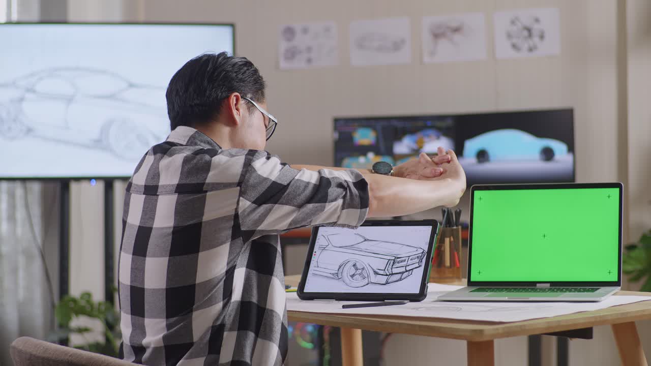 테이블릿을 에 초록색 화면 노트북과 tv와 컴퓨터를 가진 스튜디오에서 3d 전기 자동차 모델을 표시하는 동안 자동차 개념을 그리는 아시아 남성의 측면 뷰