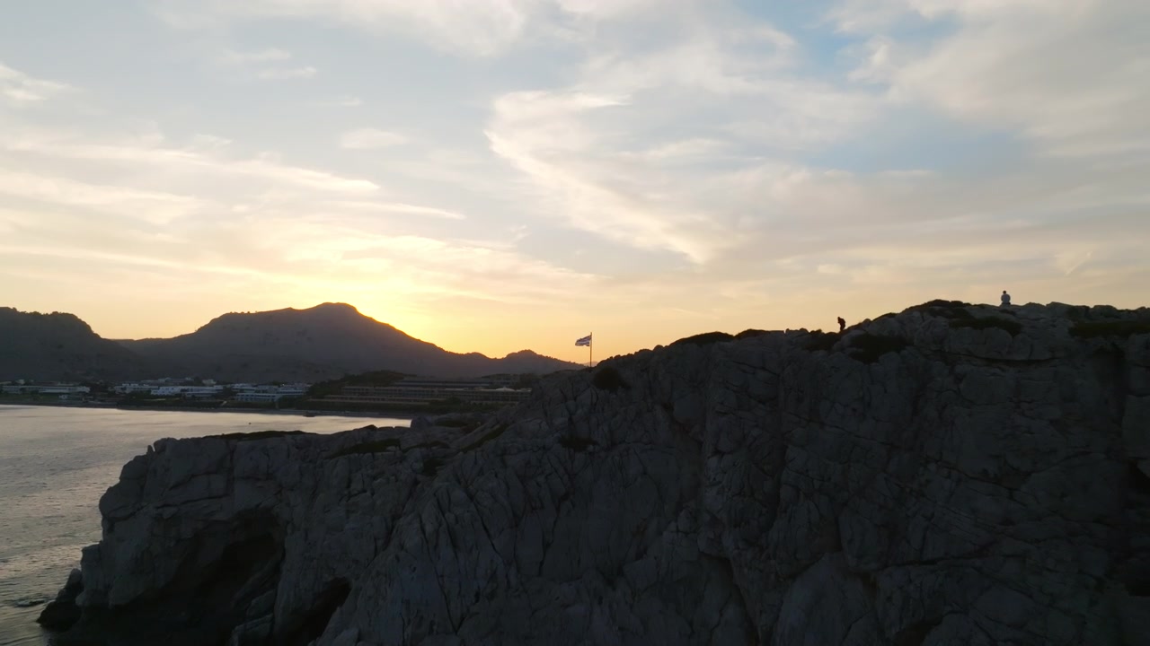 Vista aerea verso una bandiera greca, sulla costa rocciosa di Rodi, tramonto in Grecia