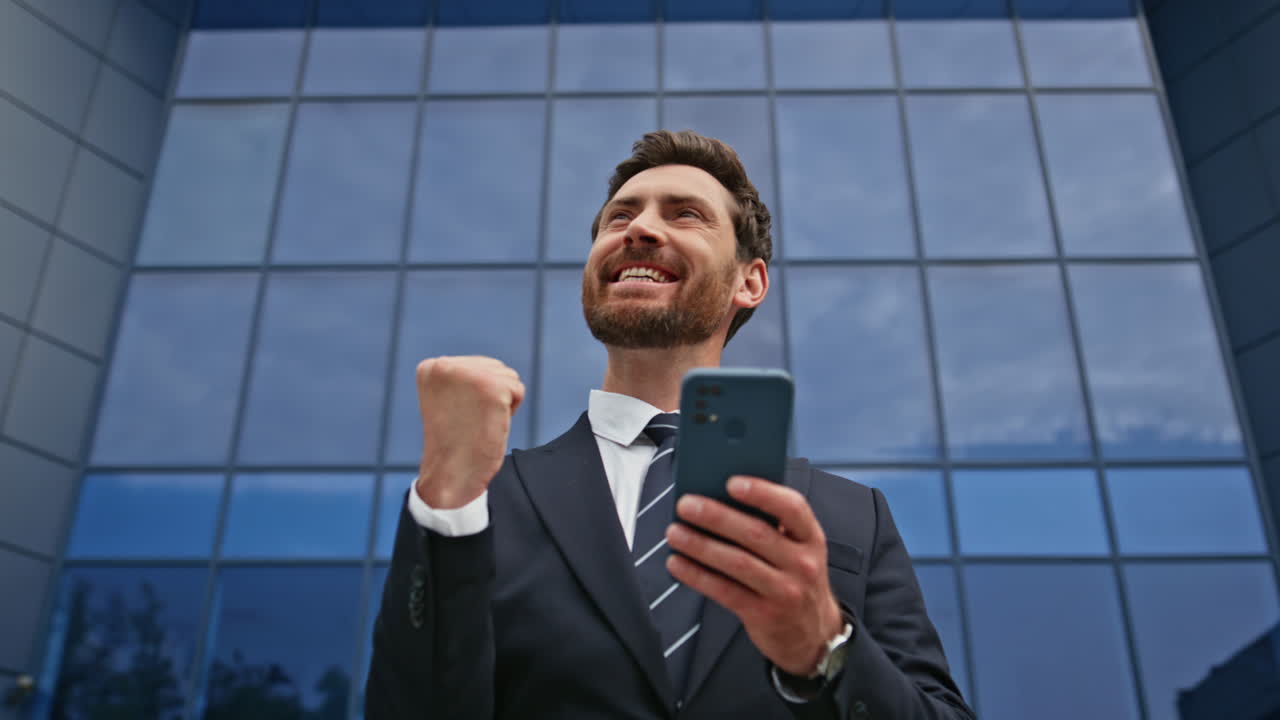 Satisfied executive browsing smartphone message outside office building closeup