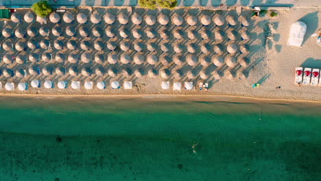 Vista-De-Arriba-Hacia-Abajo-De-La-Playa-Con-Sombrillas-En-Hanioti,-Grecia