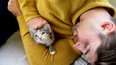 young man lying on sofa stroking his pet cat while holding her in his arms 4k 4k