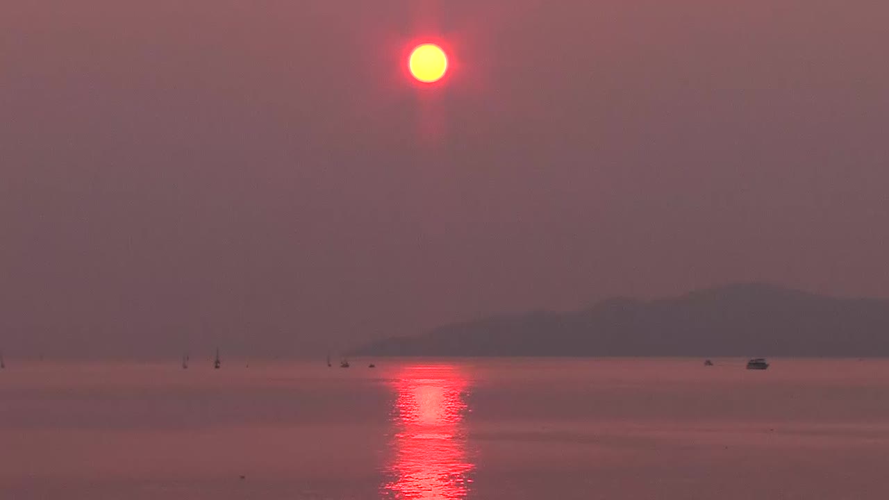 Sun setting on horizon with smoke in sky