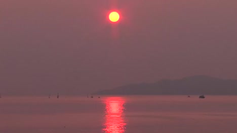 sun setting on horizon with smoke in sky