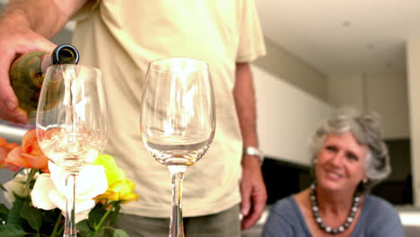 un hombre vertiendo un vaso de vino para su esposa.
