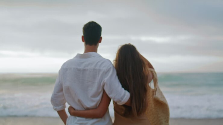 Gros plan sur un couple amoureux longeant l'océan en été. Des époux s'étreignant au bord de la mer.