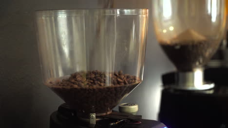 closeup of coffee machine grinder container being filled with coffee beans